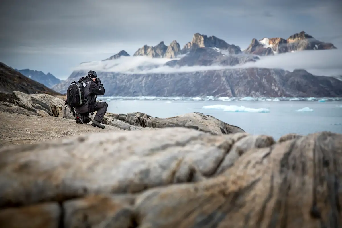 A Photographer Shooting Rugged Mountain Peaks Near Sermiligaaq In East Greenland