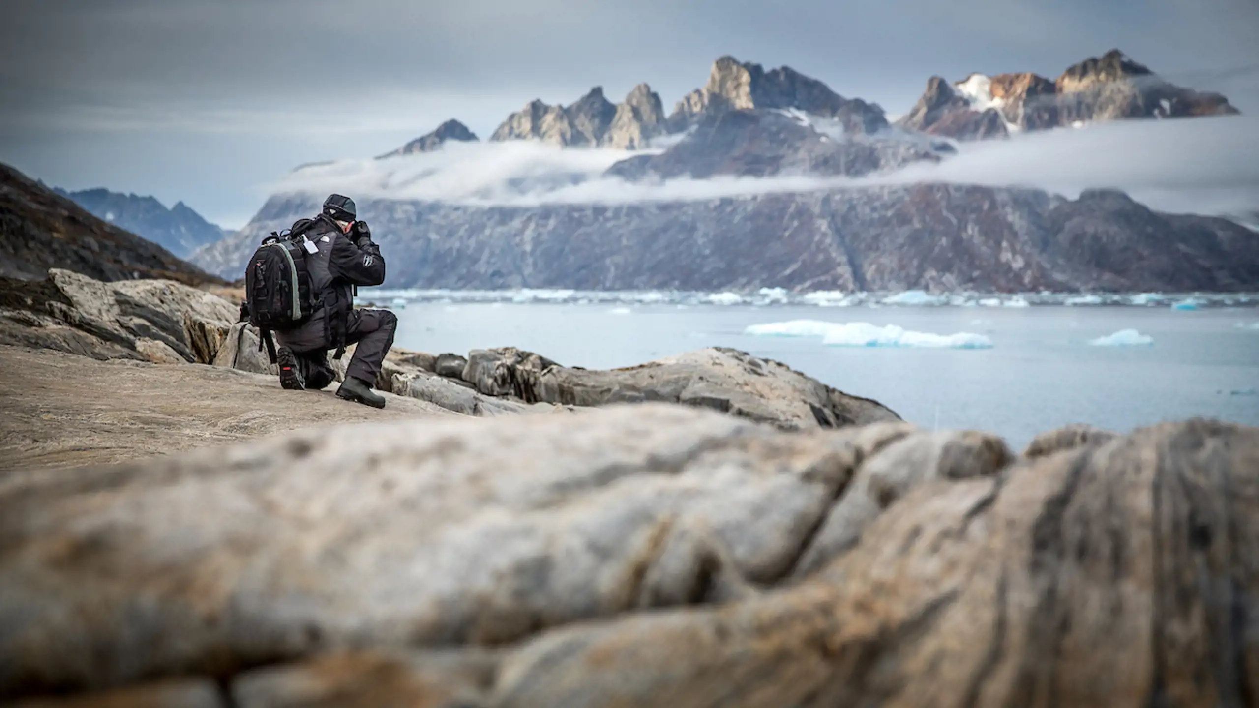 A Photographer Shooting Rugged Mountain Peaks Near Sermiligaaq In East Greenland