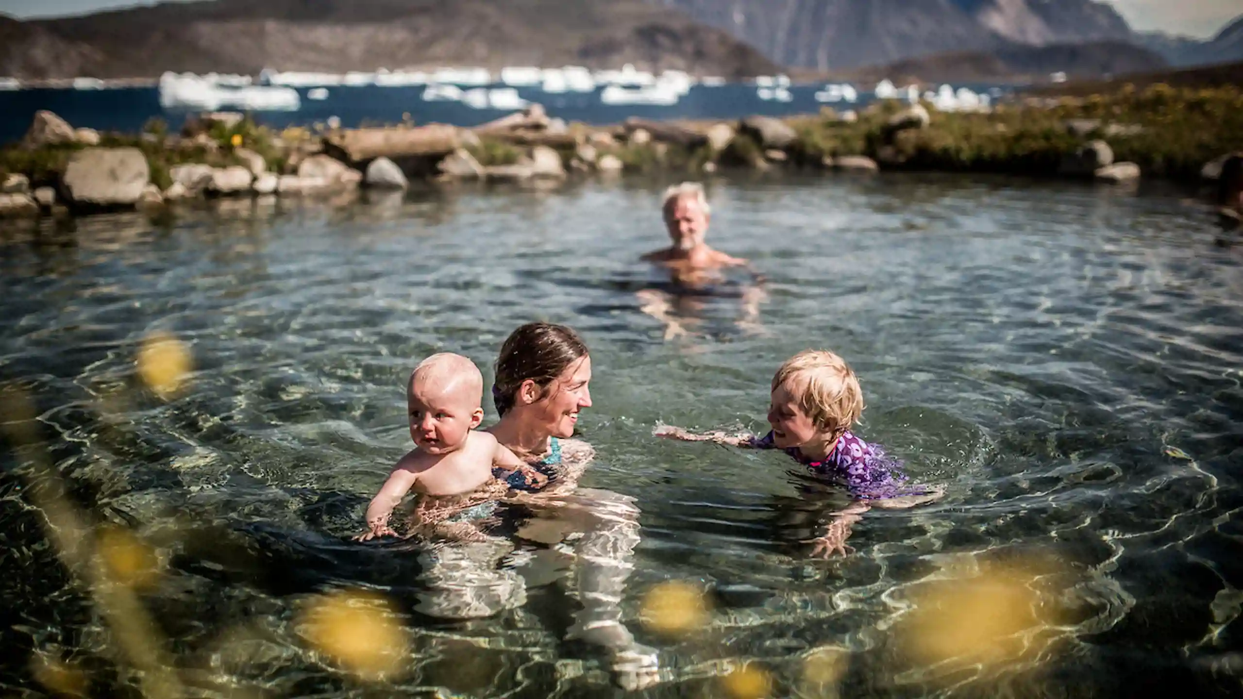 A Family Swimming In The Uunartoq Hot Springs In South Greenland