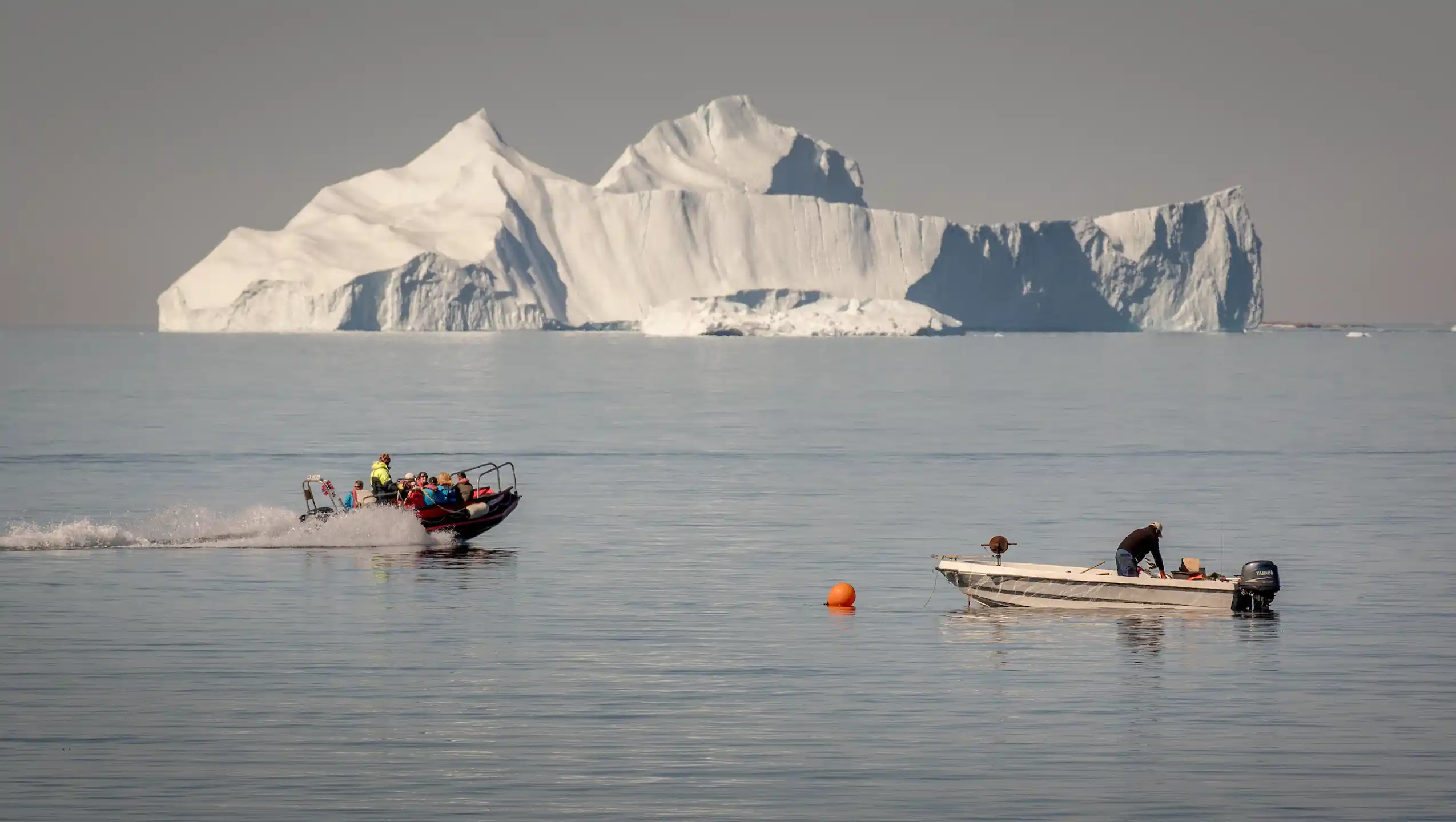 A Tenderboat From MS Fram Going Past A Fisherman At Work In Upernavik In Greenland